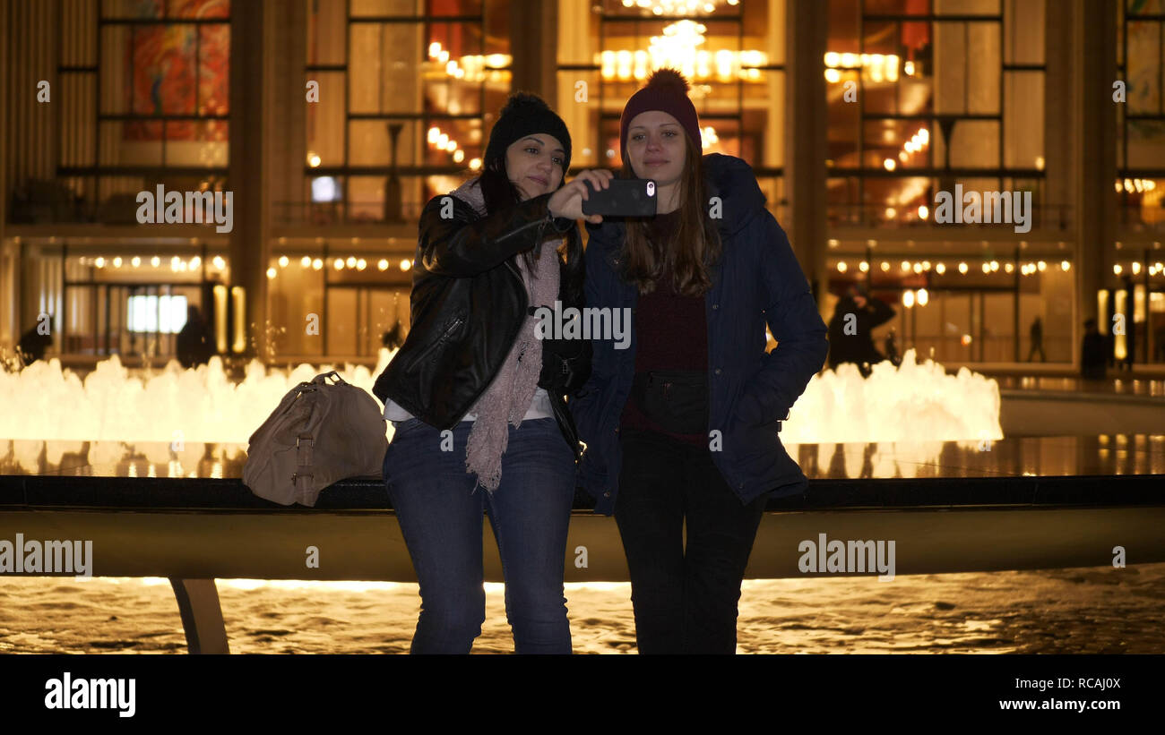 Due ragazze hanno una fantastica notte di New York durante la seduta a una fontana - NEW YORK / STATI UNITI D'America - 4 Dicembre 2018 Foto Stock