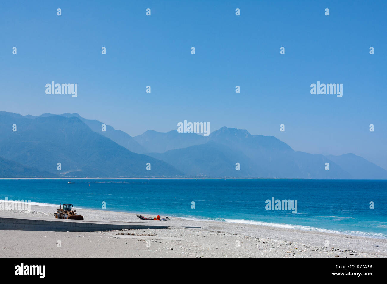 Azzurre acque dell'Oceano Pacifico il lavaggio sulla spiaggia di ciottoli con Catena Montuosa Centrale su sfondo, Chisingtan Scenic Area, Hualien, Taiwan Foto Stock