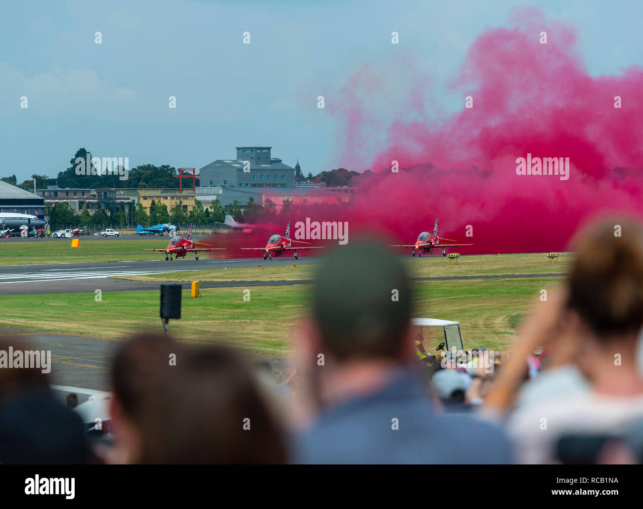 La folla guarda le frecce rosse come loro decollo per avviare la loro visualizzazione all'Airshow di Farnborough, Farnborough, Hampshire, Inghilterra, Regno Unito Foto Stock