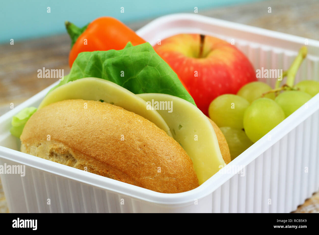 Pranzo al sacco contenente formaggio rotolo, croccante di peperone giallo e frutta fresca: Rosso mela e uva Foto Stock