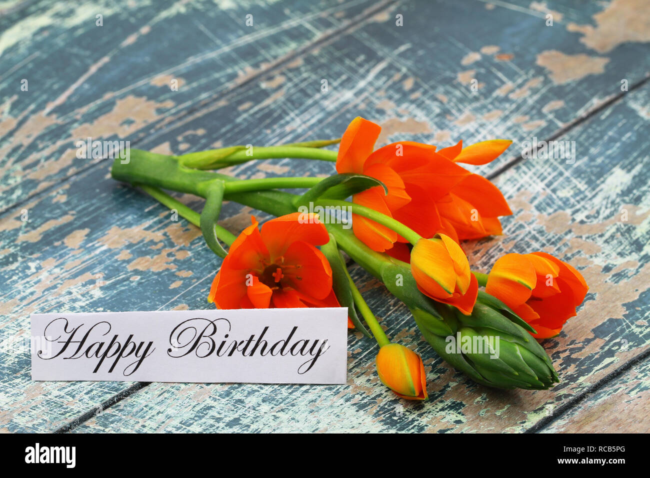 Buon compleanno card con fiori arancione sul rustico superficie in legno Foto Stock