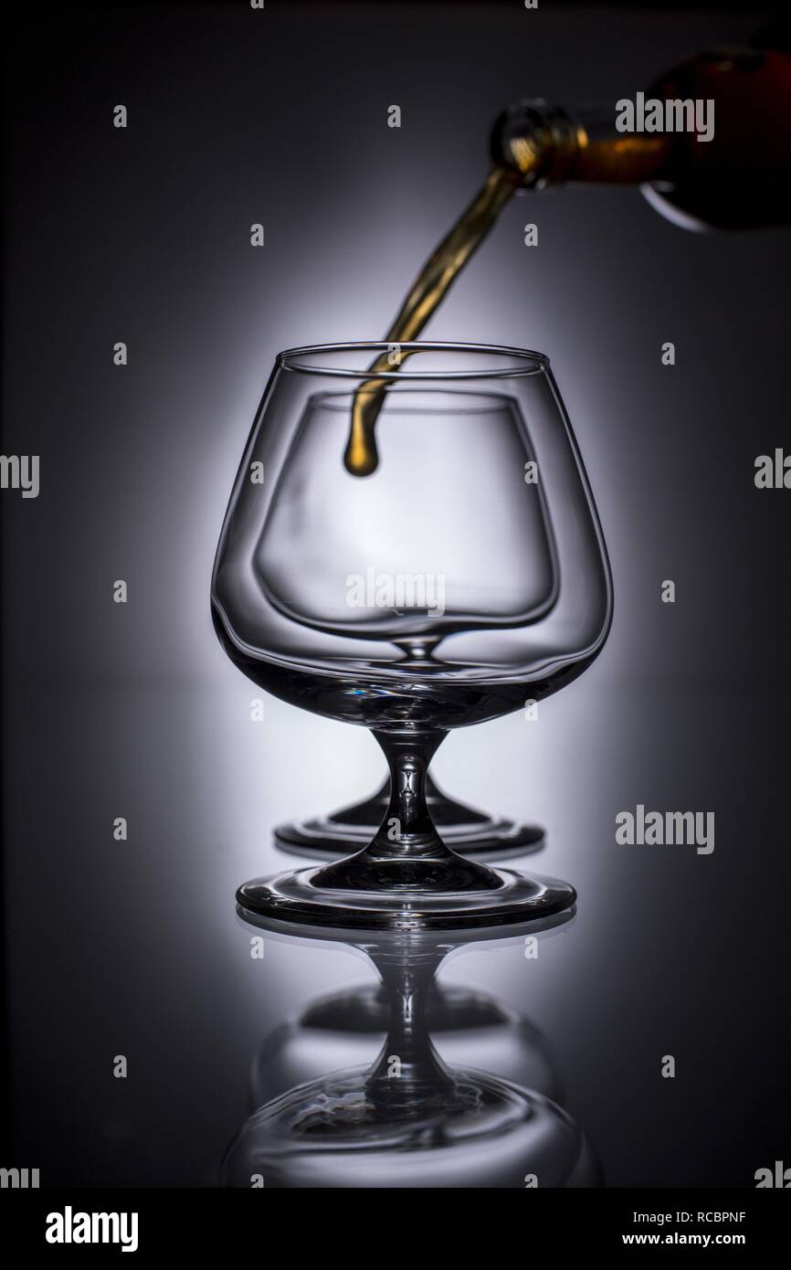 Versando il brandy in un bicchiere Foto Stock