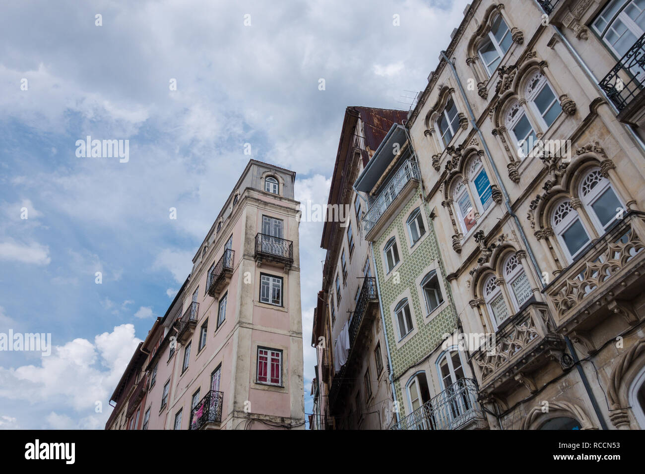 Dettagli di angolo di strada edifici con piastrelle tipiche facciate e le caratteristiche del periodo contro un cielo strutturato in Coimbra Portogallo Foto Stock