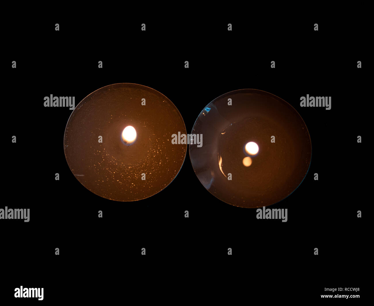 Due candele accese con una fiamma di colore arancione e isolate su uno sfondo nero Foto Stock