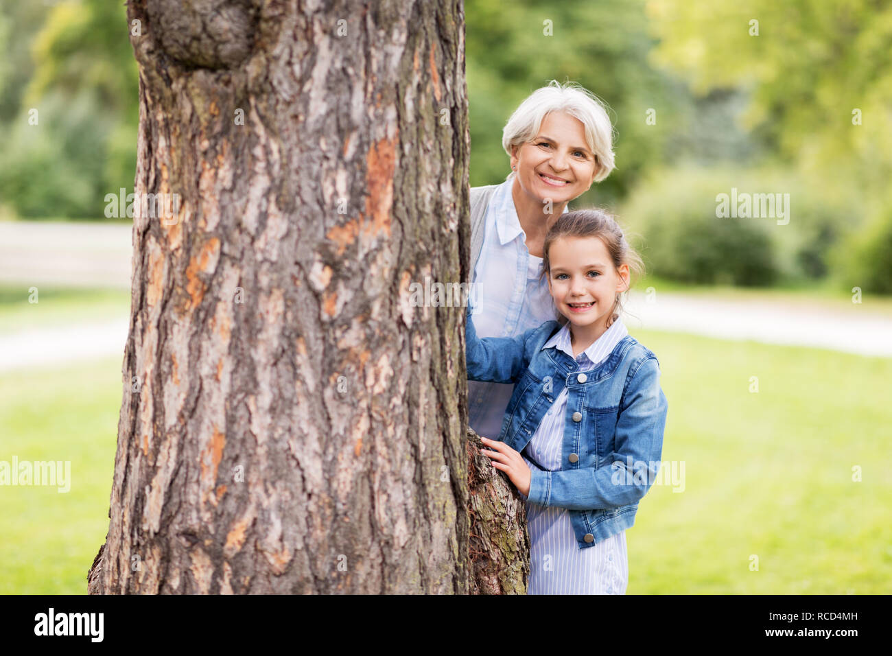 Nonna e nipote dietro albero a park Foto Stock