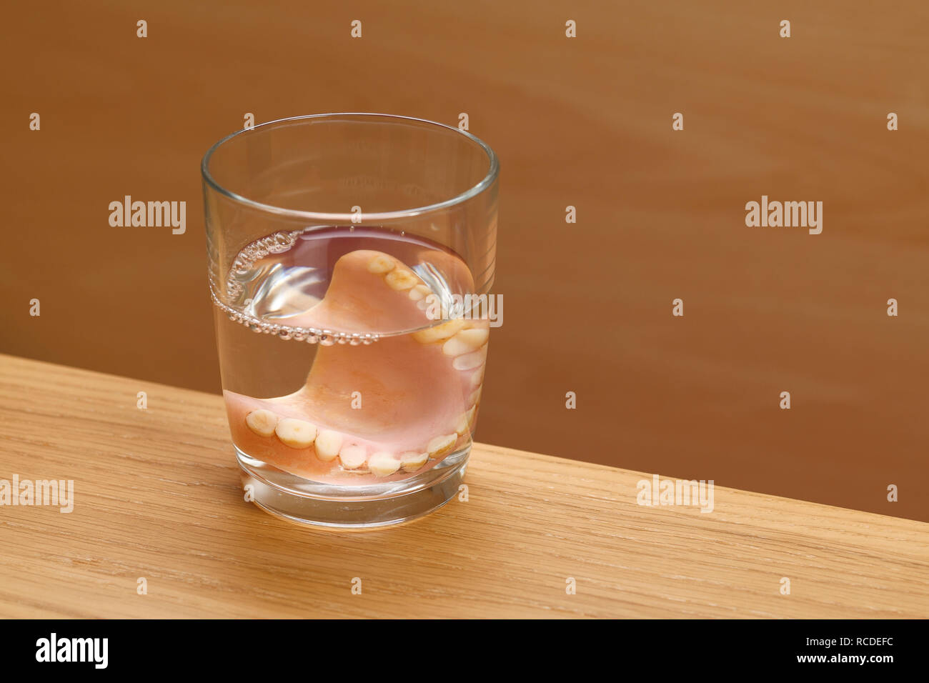 Una serie di denti finti in un bicchiere di acqua Foto Stock