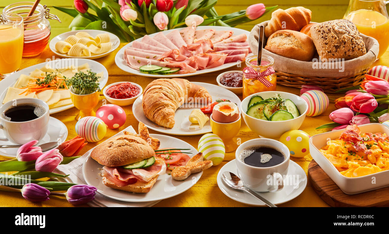 Ricca colazione a buffet con assortimento di pane, cereali, formaggi, affettati, succhi di frutta e caffè in un formato banner piena vista del telaio Foto Stock