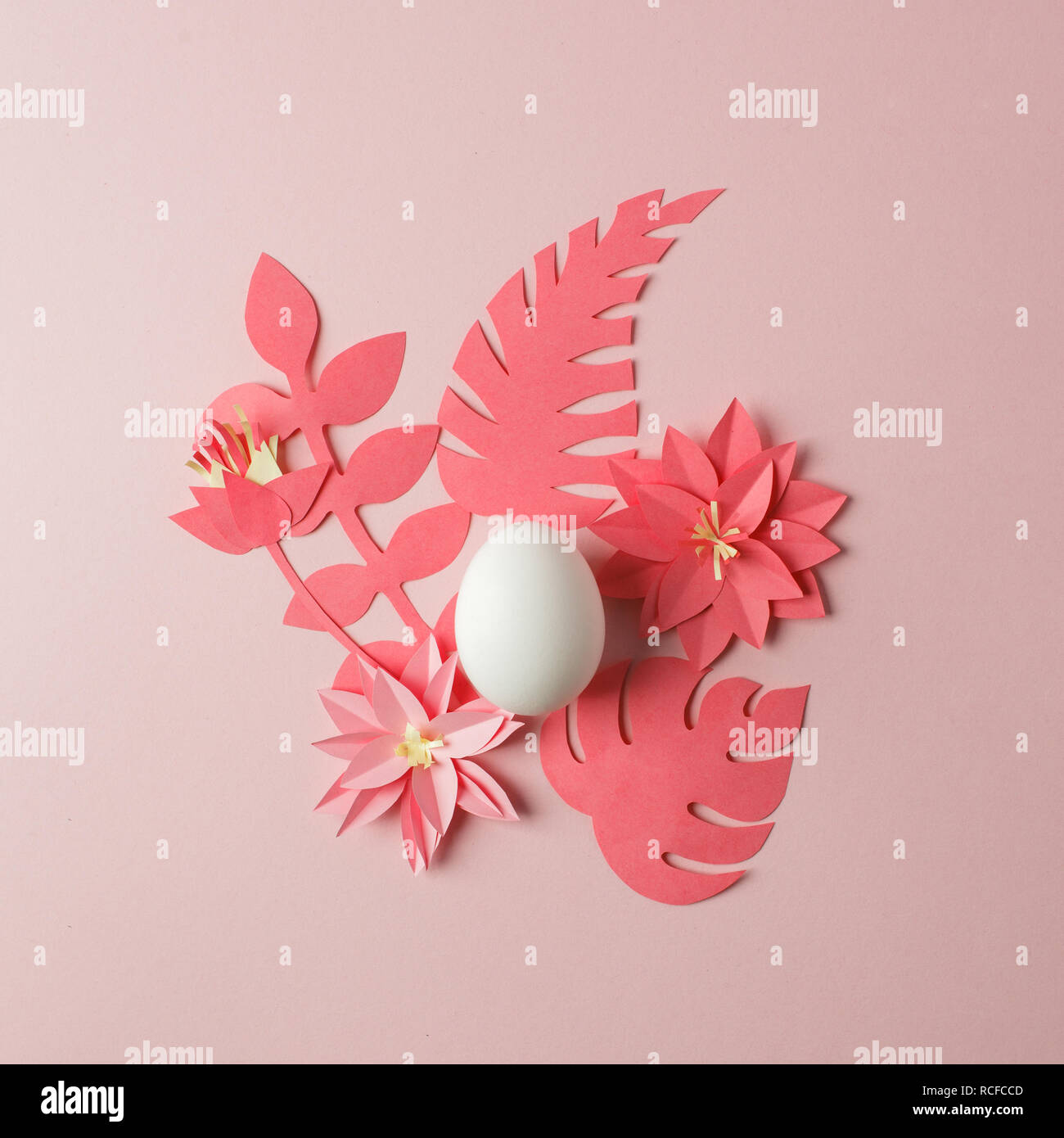 Un concetto moderno di pasqua - uovo bianco e origami papaercraft fiori e piante sul pastello rosa tabella Foto Stock