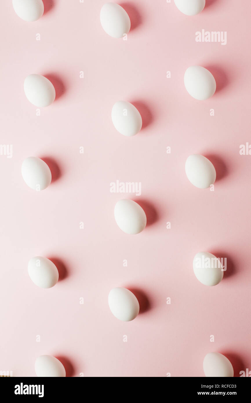 Le uova bianche su una luce sfondo rosa con la riflessione delle ombre e spazio copia. formato per la Pasqua. Laici piana, pattern Foto Stock