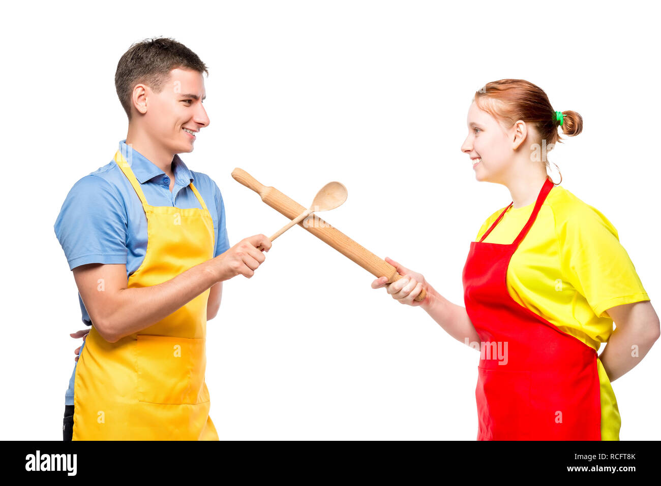 Ritratto di un uomo e di una donna in un grembiule con utensili da cucina in combattimenti su sfondo bianco Foto Stock