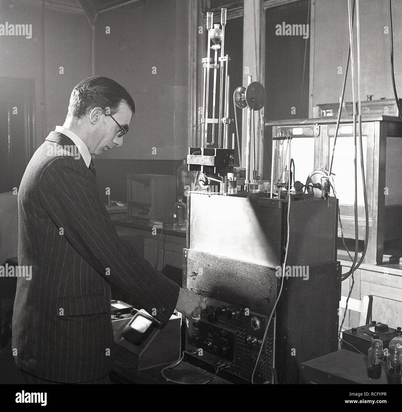 1950s, storico, all'interno di un laboratorio scientifico di ricerca, uno scienziato maschile in una tuta a a strisce utilizzando apparecchiature di test dell'epoca, Leeds University, Leeds, Inghilterra, Regno Unito Foto Stock