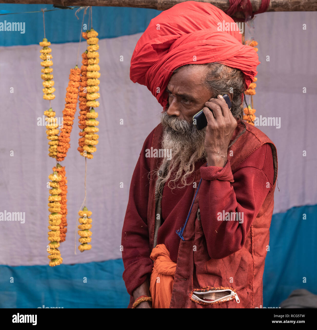 Gangasagar,campo di transito,Kolkata,un Indiano,sadhu, usingmodern cellulare, Kolkata,l'India. Foto Stock