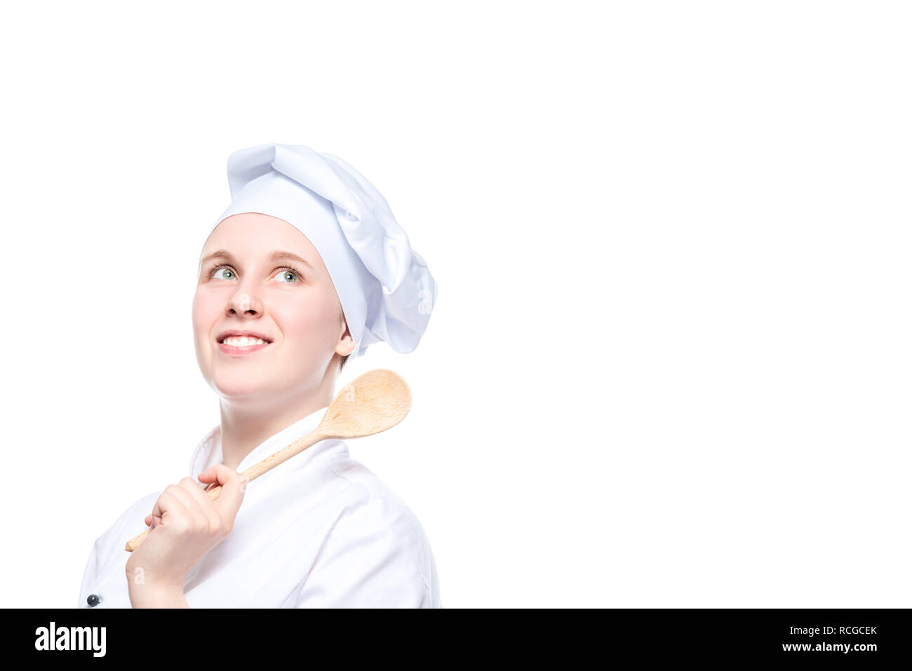 Ritratto orizzontale di una felice sognando cook con un cucchiaio di legno su uno sfondo bianco, posto per l'iscrizione sulla destra Foto Stock