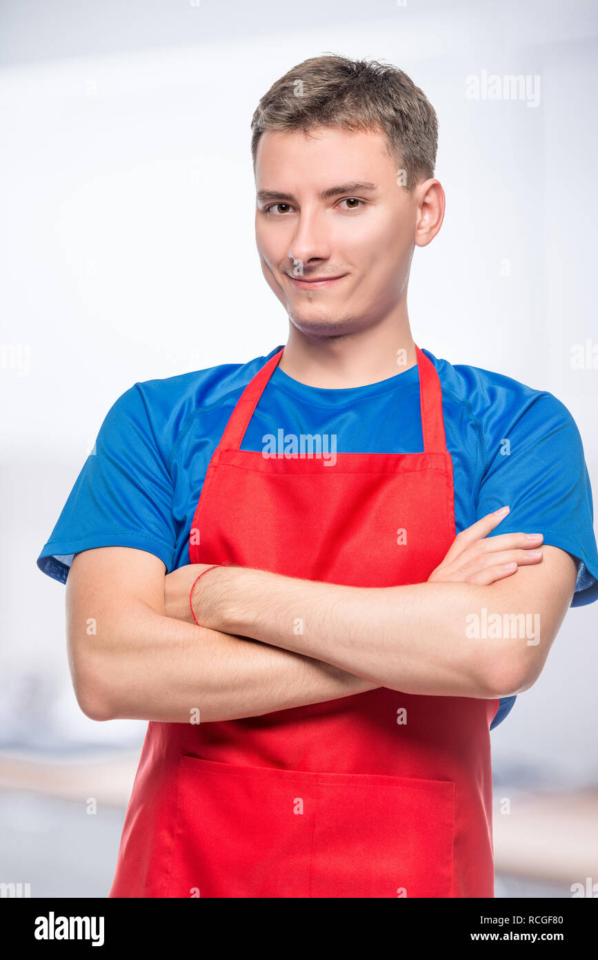 Felice ritratto di un uomo in un grembiule rosso su sfondo grigio Foto Stock