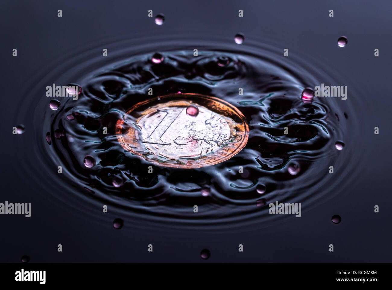 Colore rosso goccia d'acqua schizzi su un Euro e stagno inglese sterling coin Foto Stock