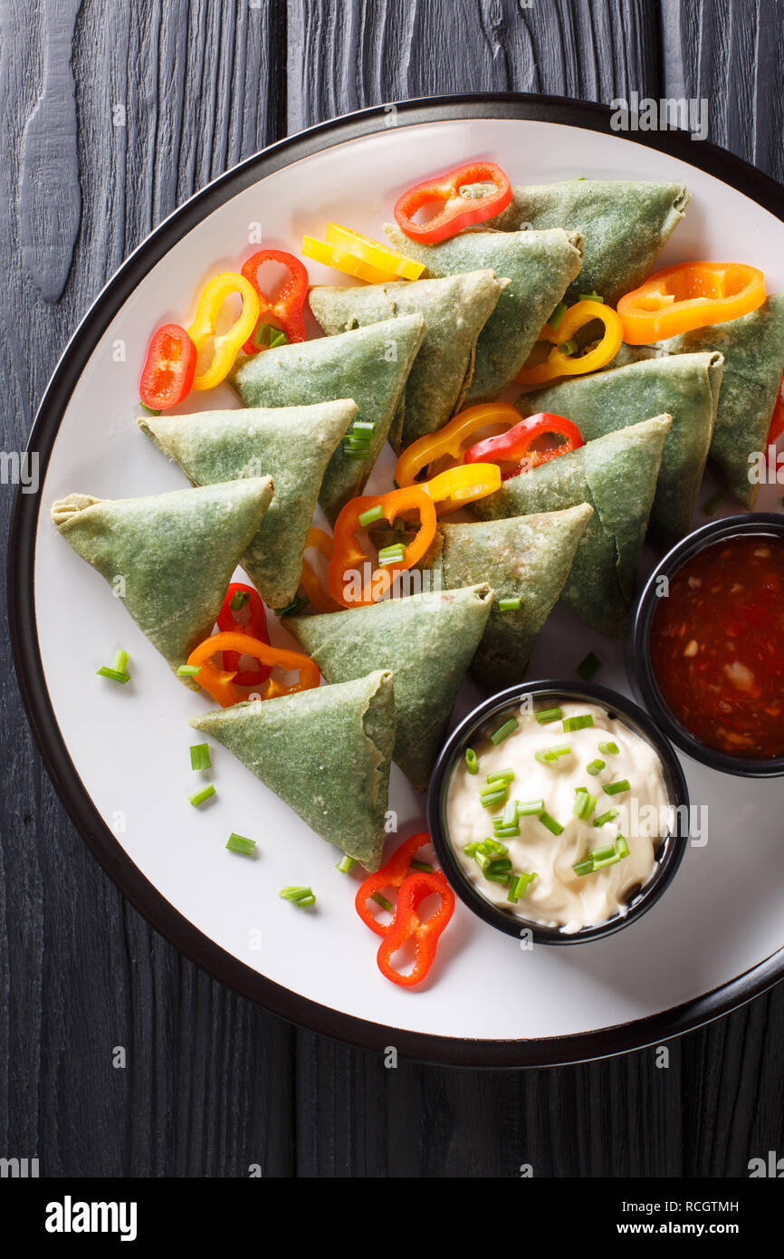 Gli spinaci vegetariana samosa con salse close-up su una piastra sul tavolo. Verticale in alto vista da sopra Foto Stock