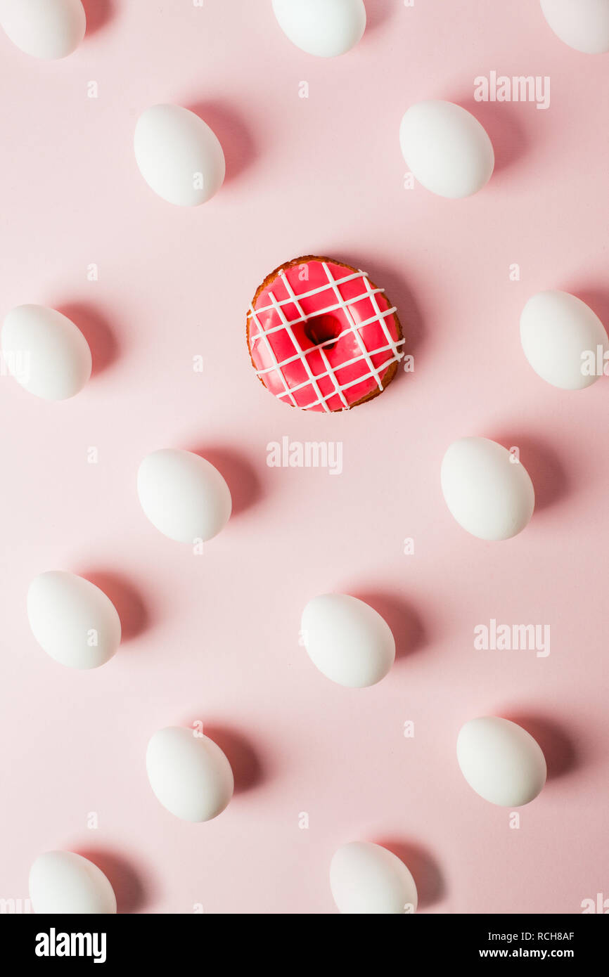 La pasqua le uova bianche ripetizione con l'ombra e la ciambella rosa rosa su sfondo color pastello, errore di sistema Foto Stock