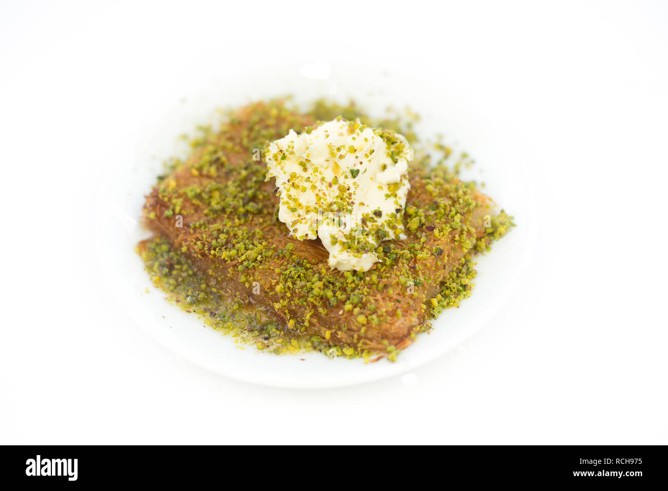 Tradizionale dessert turco come noto ' Kunefe ' o Kunafah o Kunafeh o Kunafa Kadayif. Medio oriente, dessert al pistacchio e crema su bianco isolato Foto Stock