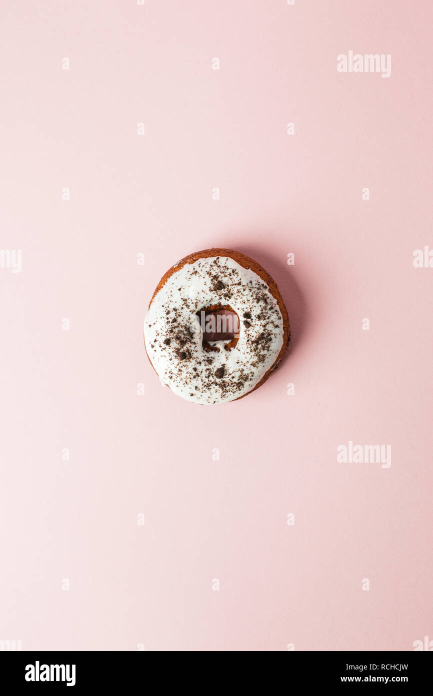 Ciambella al cioccolato con glassa bianca su sfondo rosa. Vista dall'alto. Il minimo di cibo e il concetto di partito Foto Stock