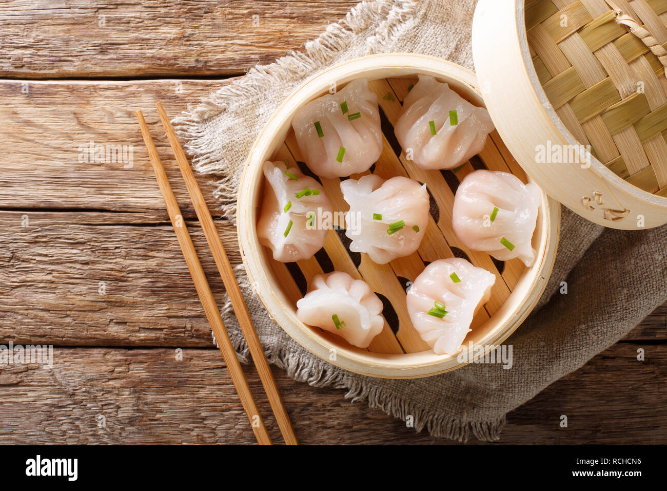 Gnocchi fatti in casa a base di dim sum con Gamberi Ripieni di close-up in un sistema per la cottura a vapore in bambù casella della tabella. Parte superiore orizzontale vista da sopra Foto Stock
