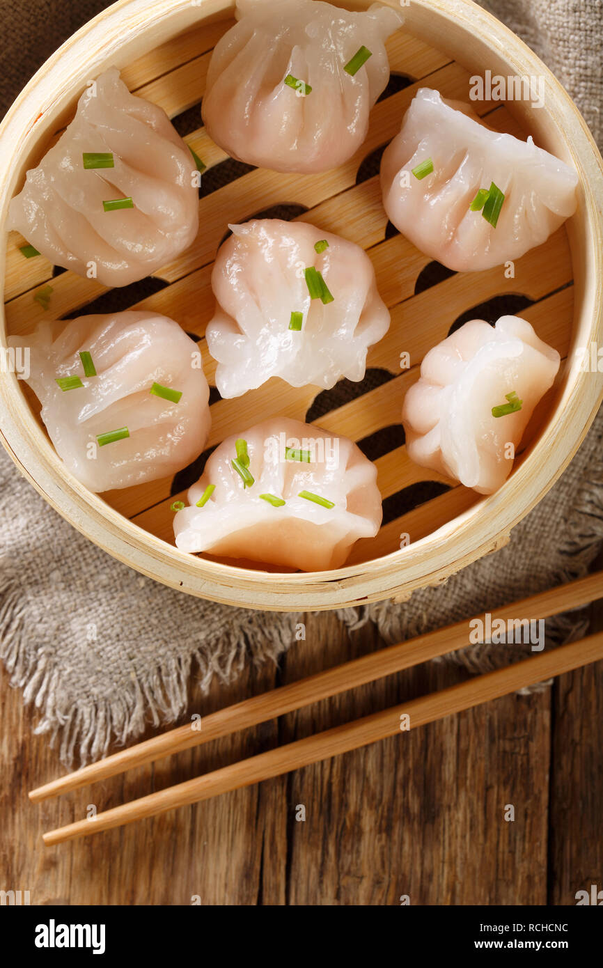 Gnocchi fatti in casa a base di dim sum con Gamberi Ripieni di close-up in un sistema per la cottura a vapore in bambù casella della tabella. Verticale in alto vista da sopra Foto Stock