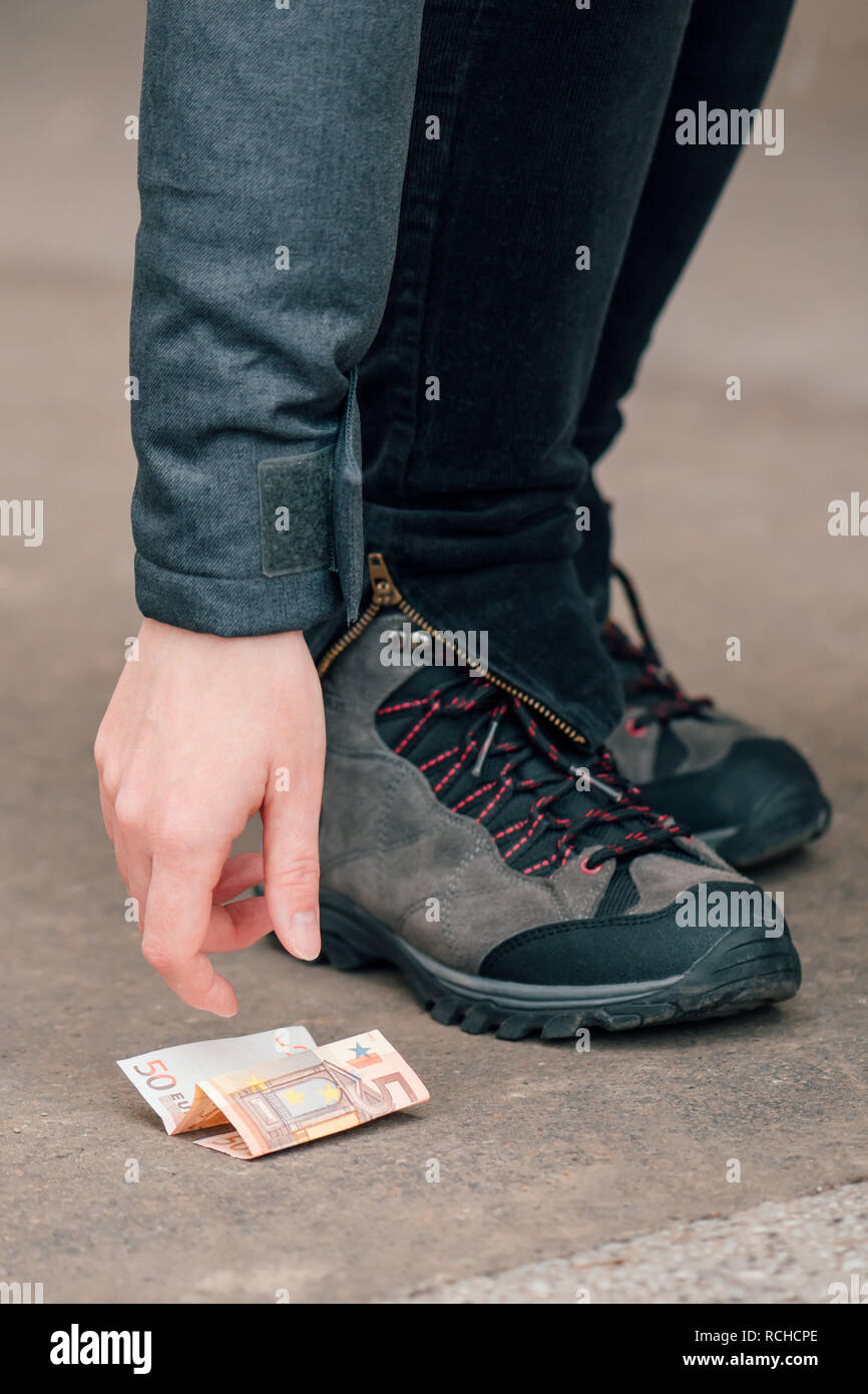 Per fortuna la donna di prelevare denaro trovato sulla pavimentazione stradale, cinquanta euro sul terreno Foto Stock