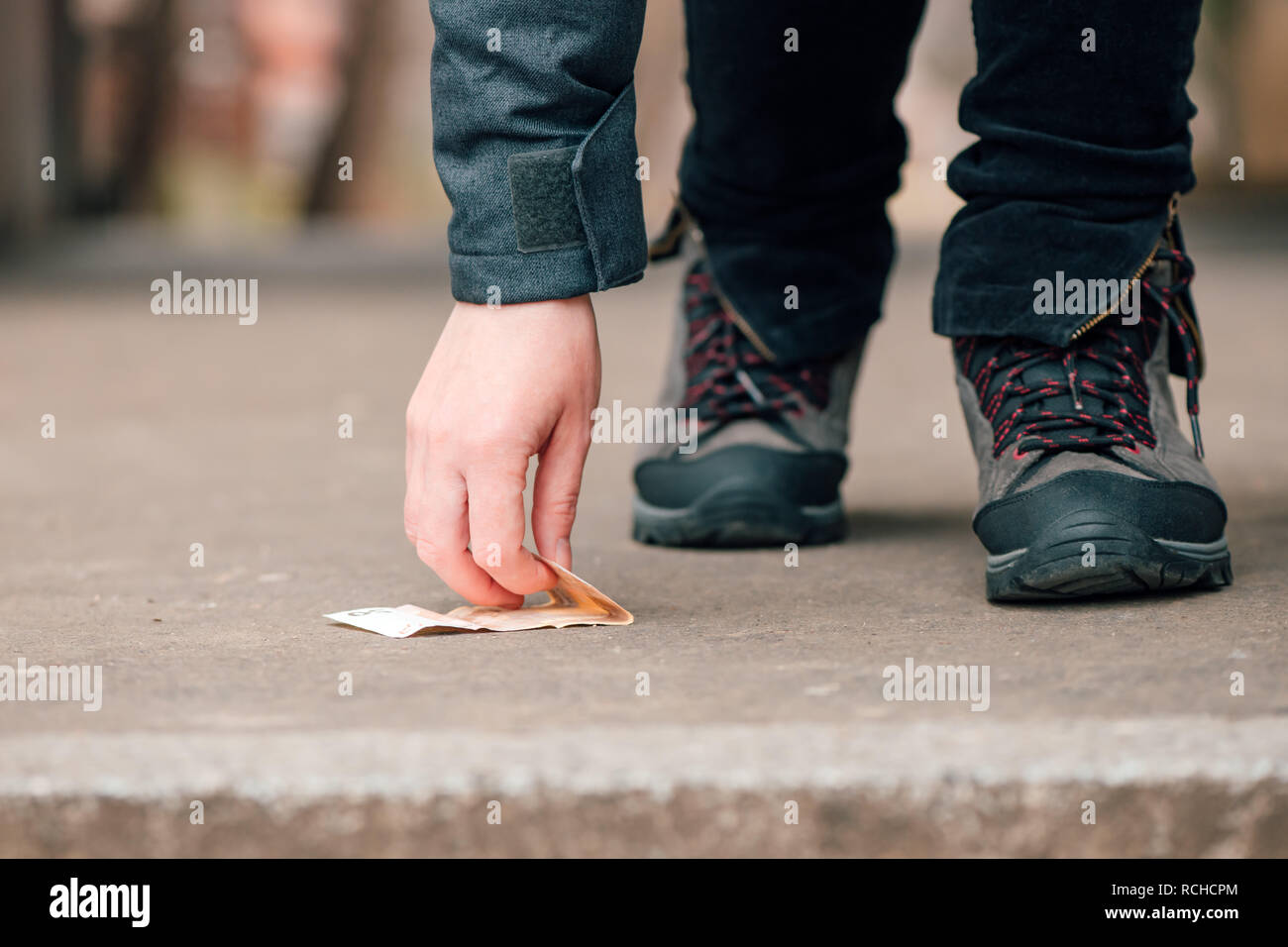 Per fortuna la donna di prelevare denaro trovato sulla pavimentazione stradale, cinquanta euro sul terreno Foto Stock