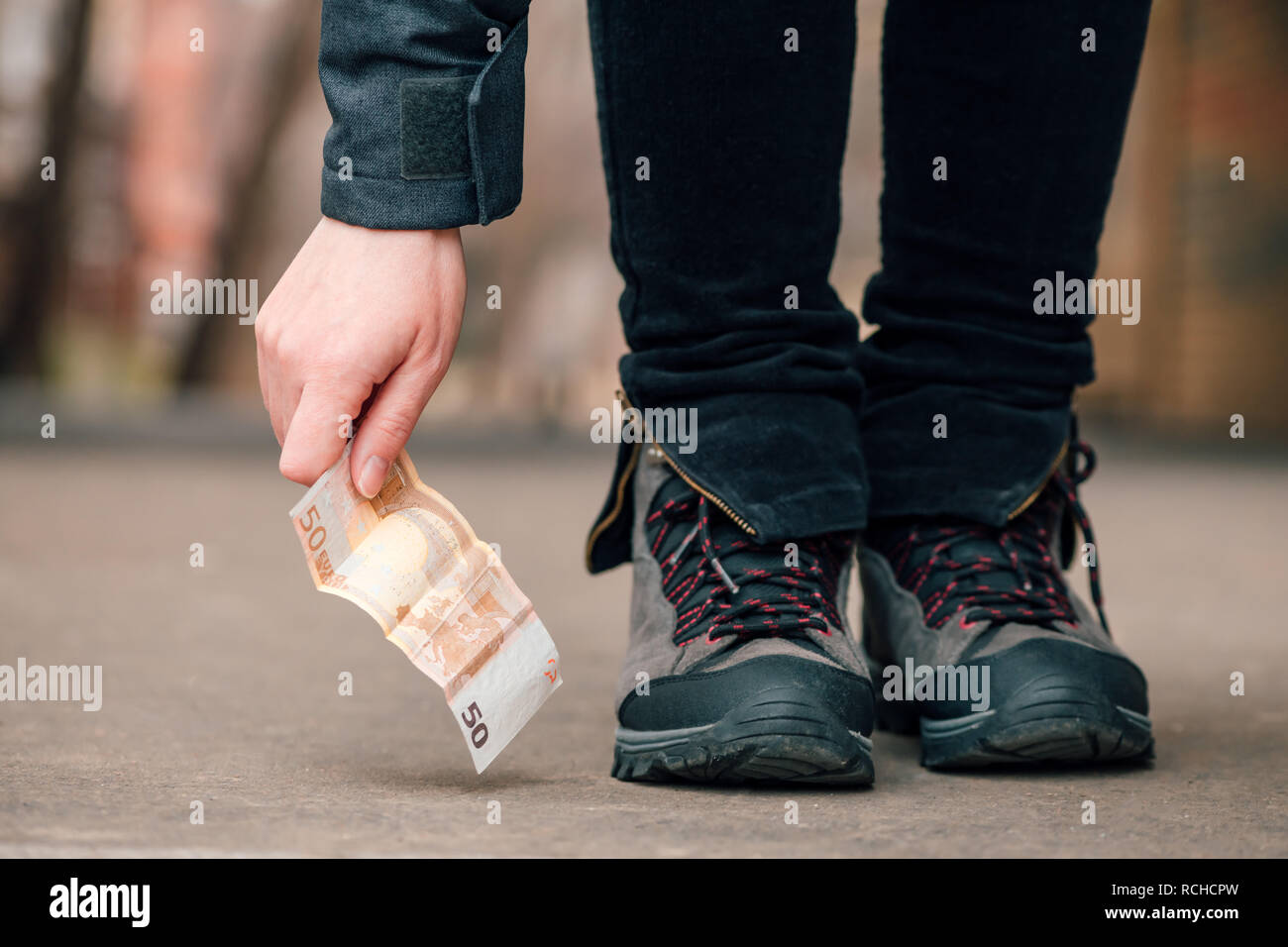 Per fortuna la donna di prelevare denaro trovato sulla pavimentazione stradale, cinquanta euro sul terreno Foto Stock