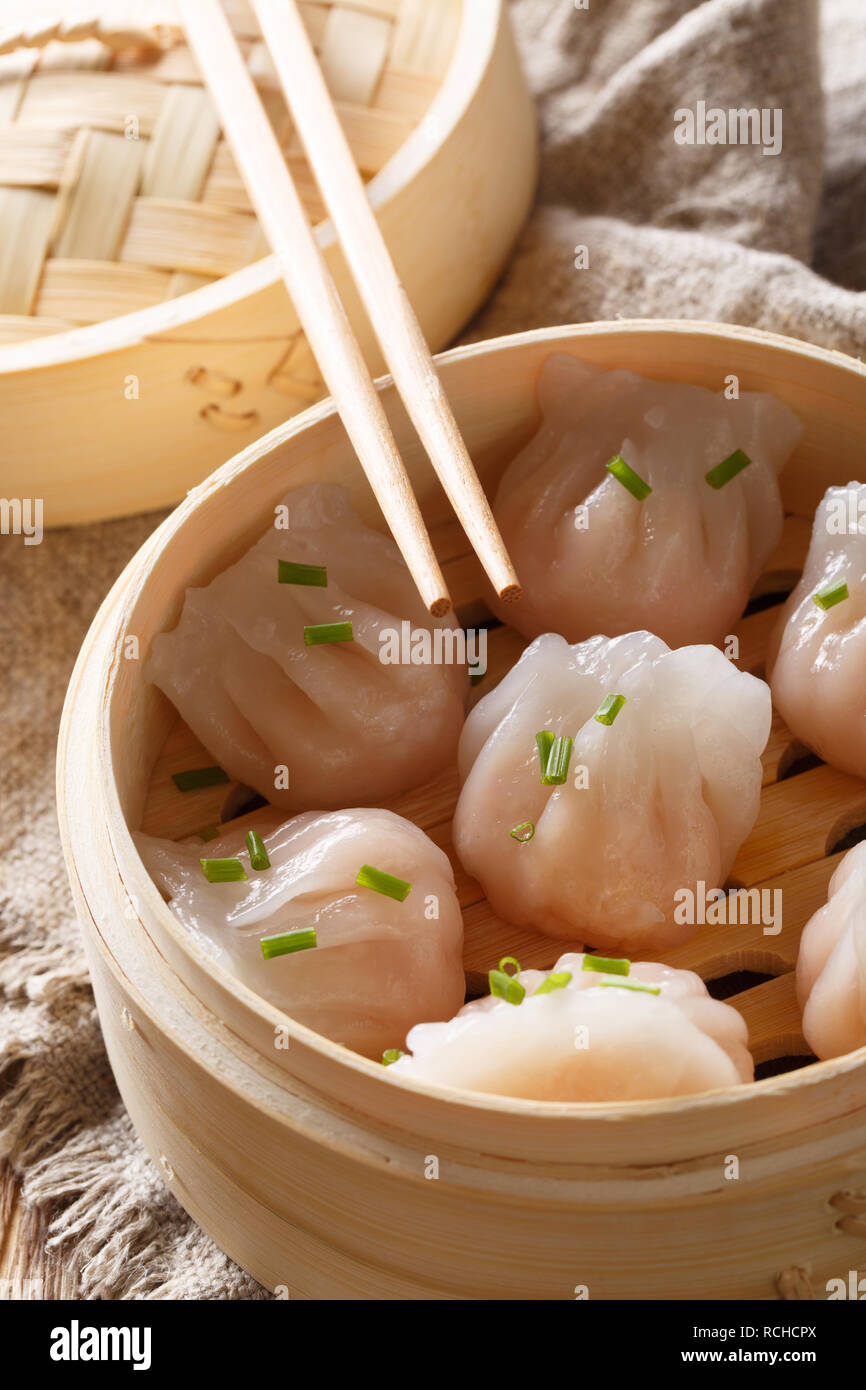 Gnocchi fatti in casa a base di dim sum con Gamberi Ripieni di close-up in un sistema per la cottura a vapore in bambù casella sulla tavola verticale. Foto Stock