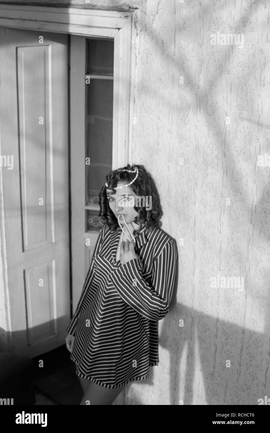 Giovane donna che indossa un mini dress in piedi in un vano della porta fa roteare una collana indossa degli anni settanta Ungheria Foto Stock