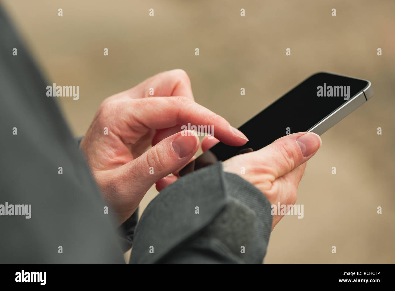 La donna si utilizza lo smartphone su strada in inverno, casual femmina adulta è messaggio di digitazione sul moderno telefono cellulare, dispositivo di messa a fuoco selettiva Foto Stock