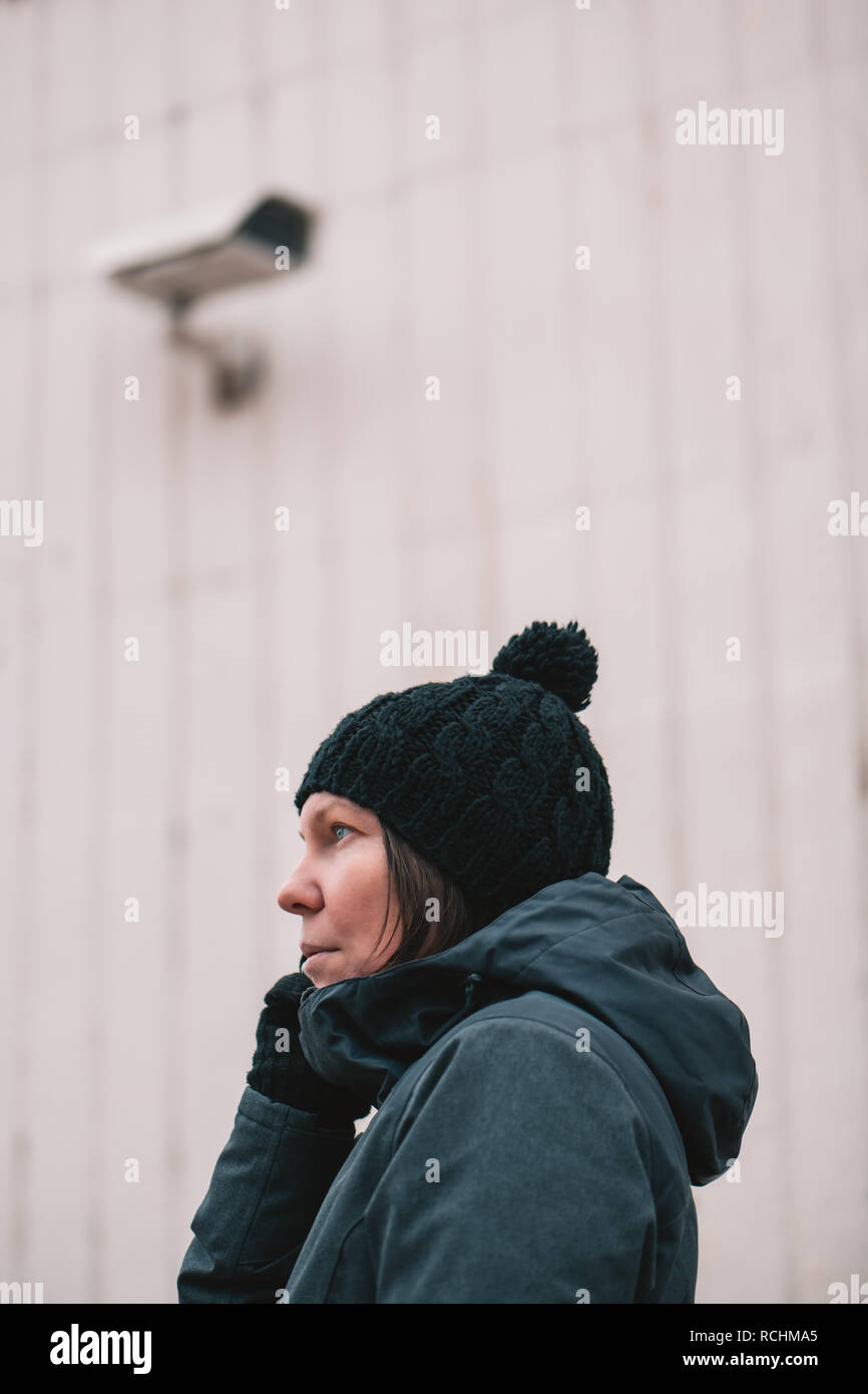 Donna che parla al telefono cellulare in strada con sorveglianza TVCC per il monitoraggio della telecamera Foto Stock