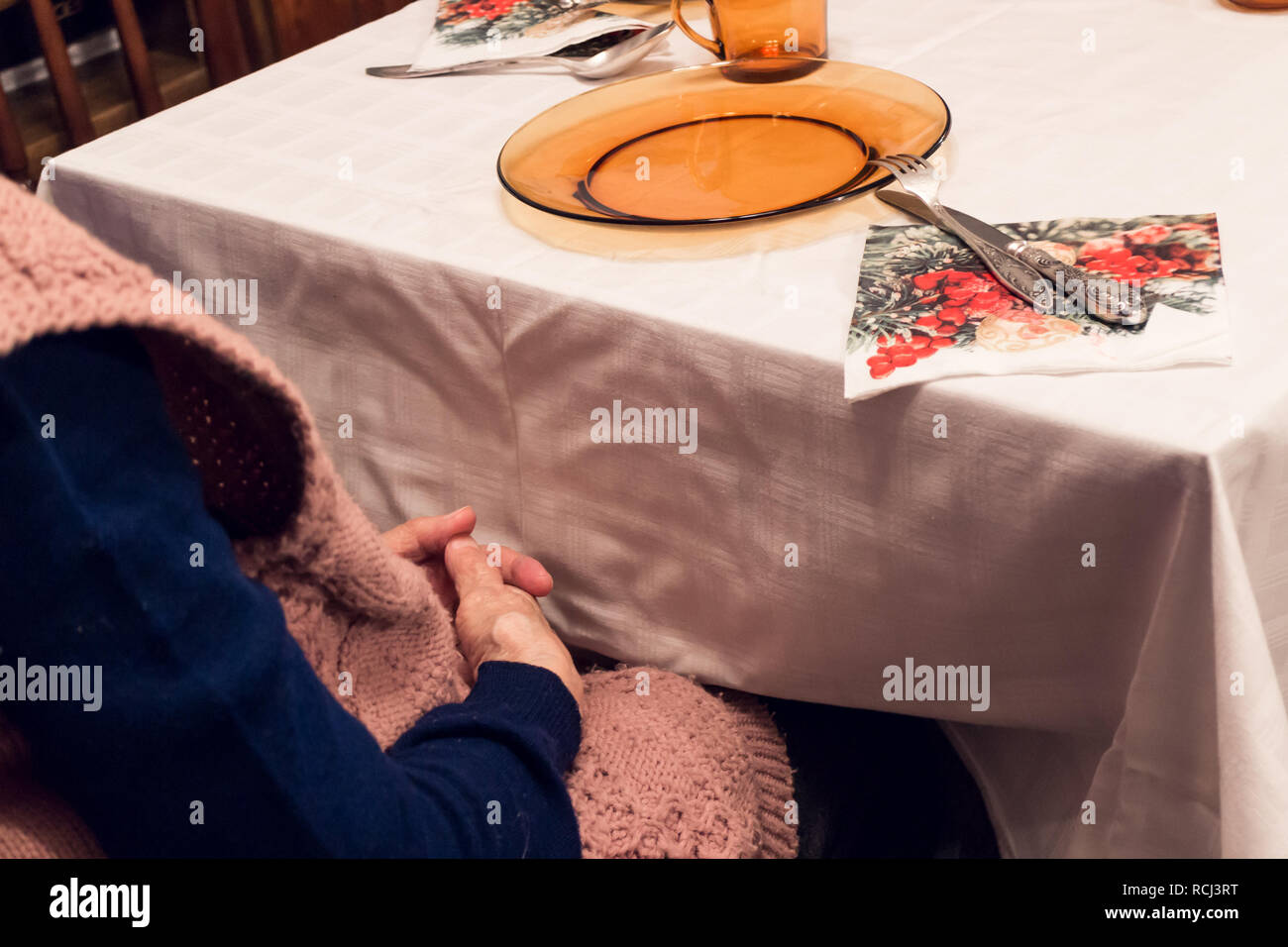 Il vecchio donna seduta al tavolo di pelle rugosa sulle mani Foto Stock