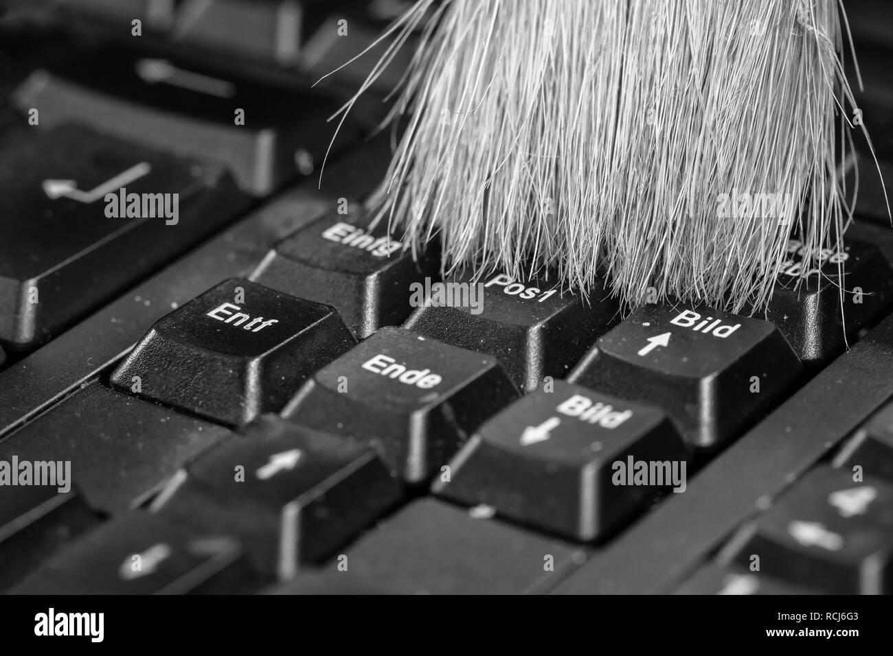 Pulizia della tastiera del computer con una spazzola in bianco e nero Foto Stock