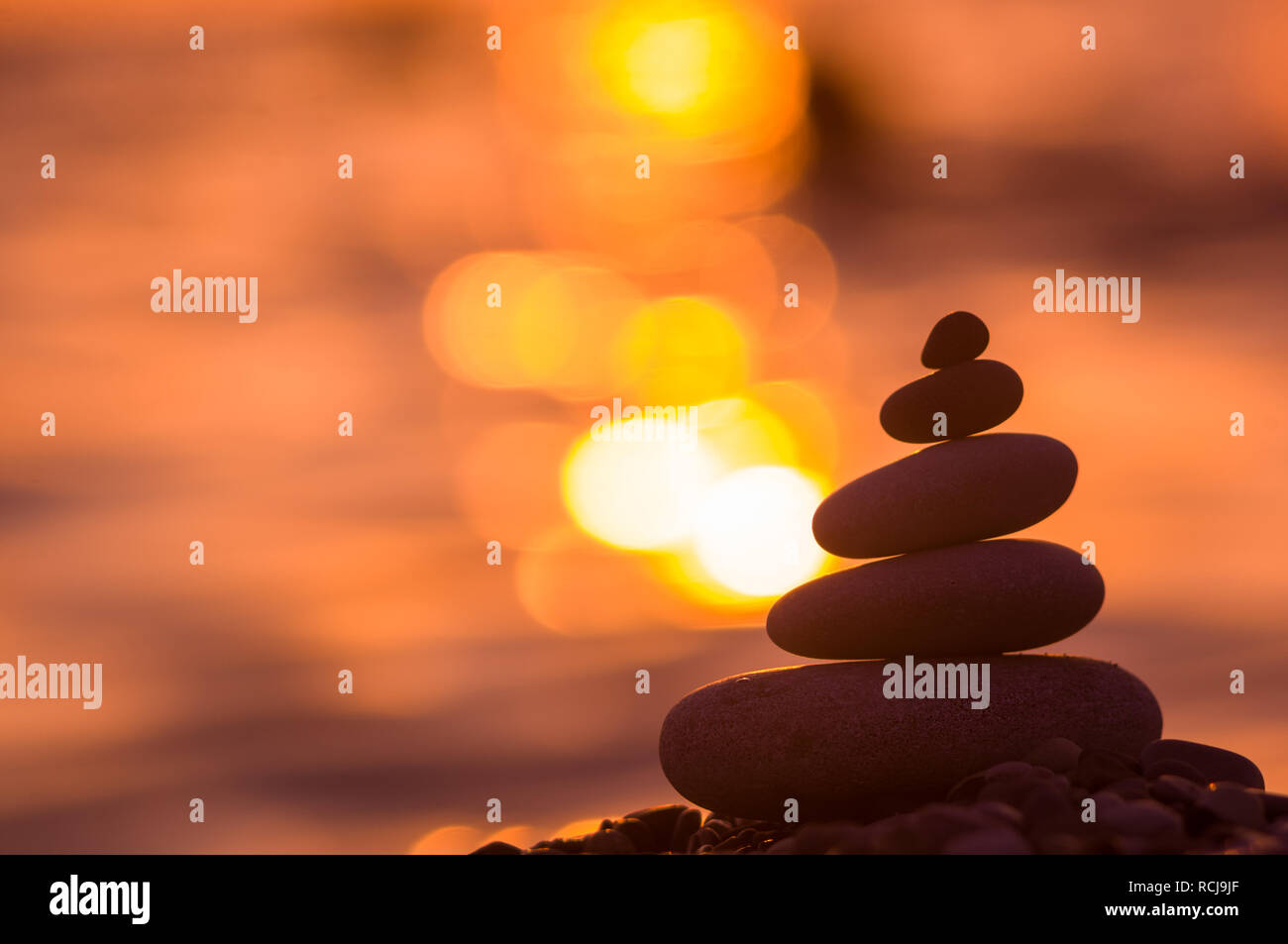 Piramide piegata Zen pietre ghiaia sul mare spiaggia al tramonto Foto Stock