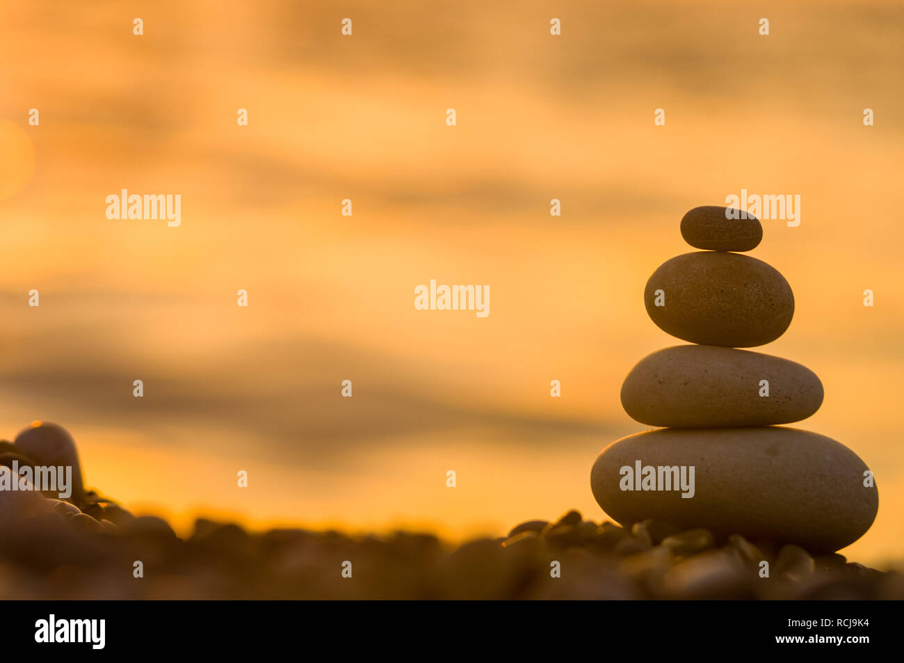 Piramide piegata Zen pietre ghiaia sul mare spiaggia al tramonto Foto Stock