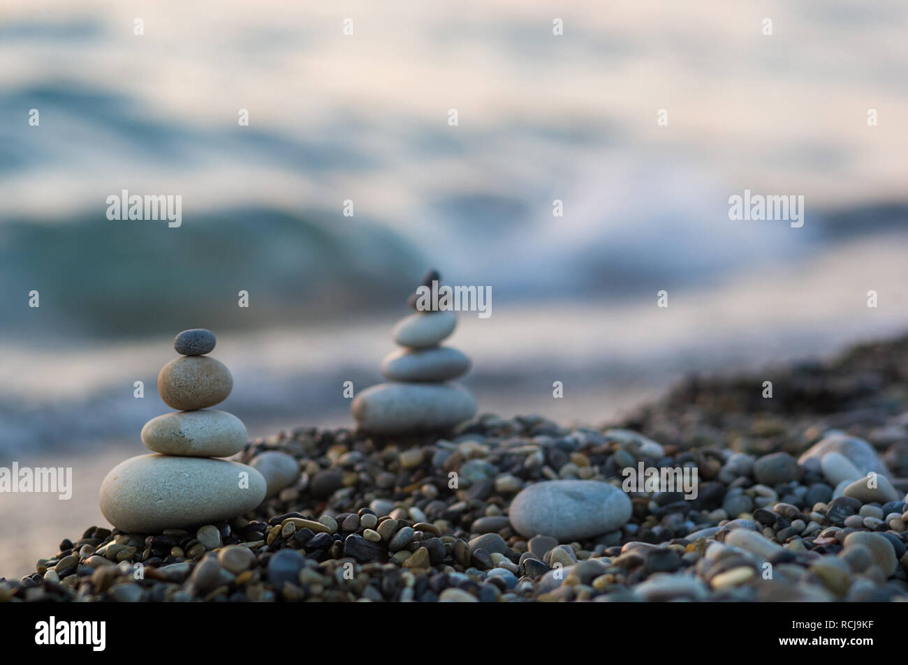 Piramide piegata Zen pietre ghiaia sul mare spiaggia al tramonto Foto Stock