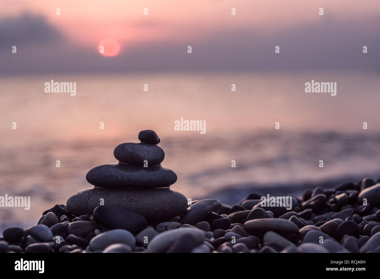Piramide piegata Zen pietre ghiaia sul mare spiaggia al tramonto Foto Stock