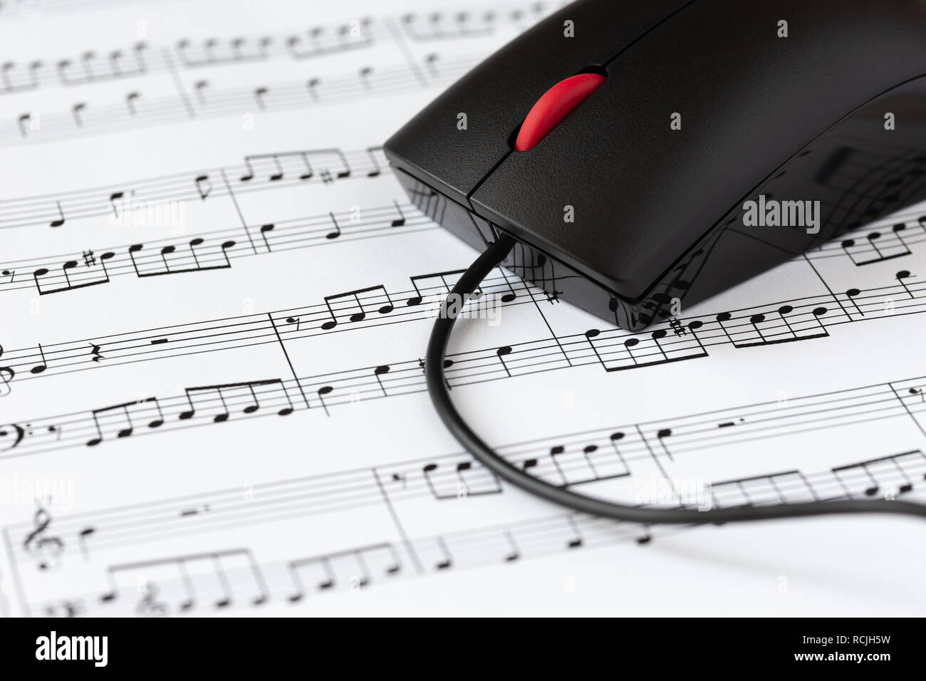 Il mouse del computer su un foglio con le note musicali, close-up con il fuoco selettivo. Il concetto di digitalizzazione di musica Foto Stock