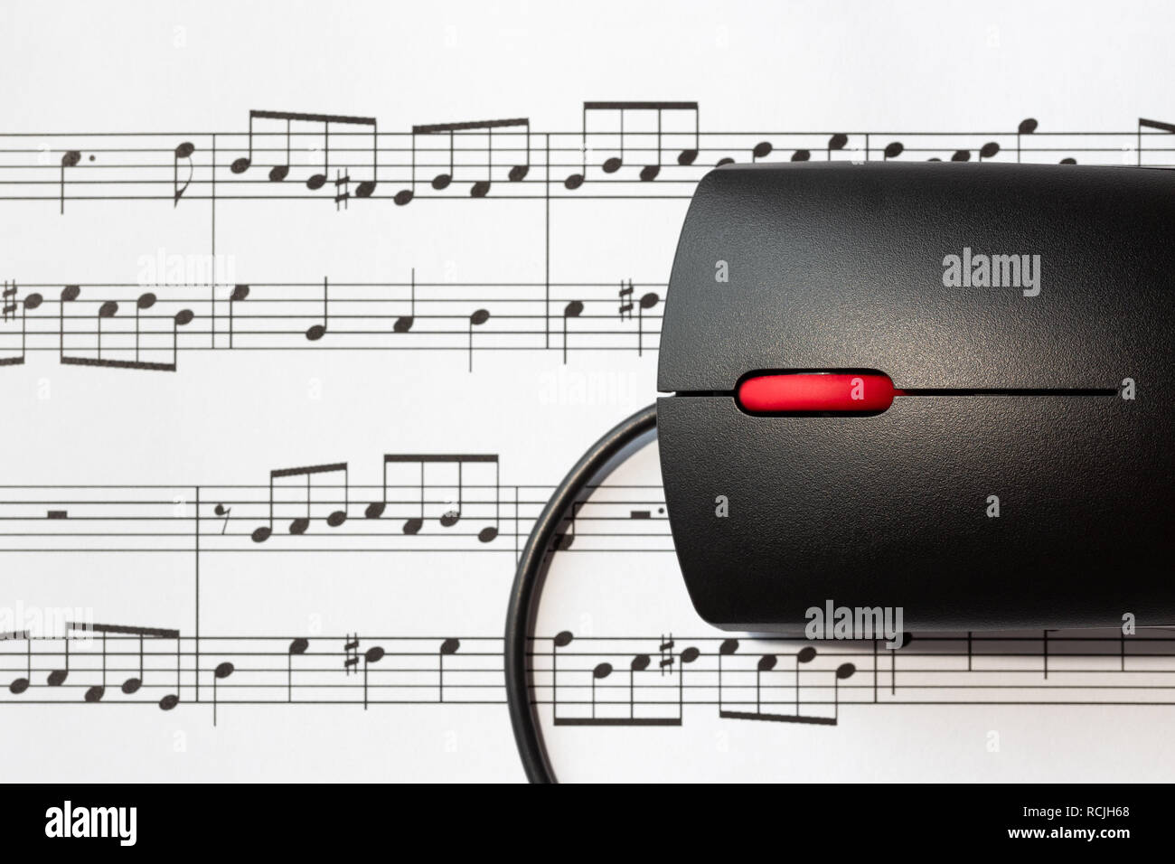 Il mouse del computer su un foglio con le note musicali, close-up con il fuoco selettivo. Il concetto di digitalizzazione di musica Foto Stock