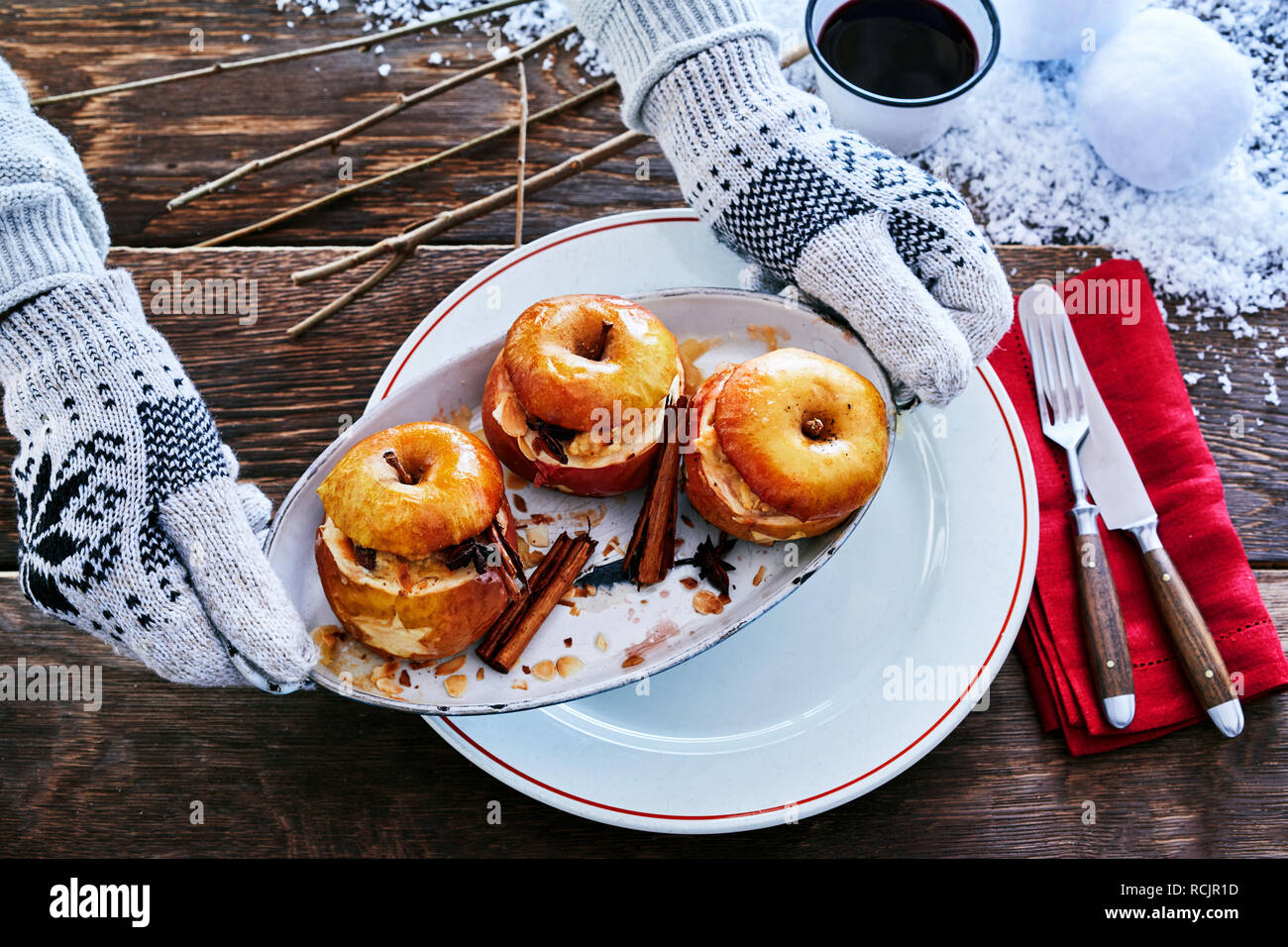 Mani guantate serve speziata cotta dessert apple con cannella su una piastra di metallo in corrispondenza di un inverno di barbecue con neve sul tavolo Foto Stock