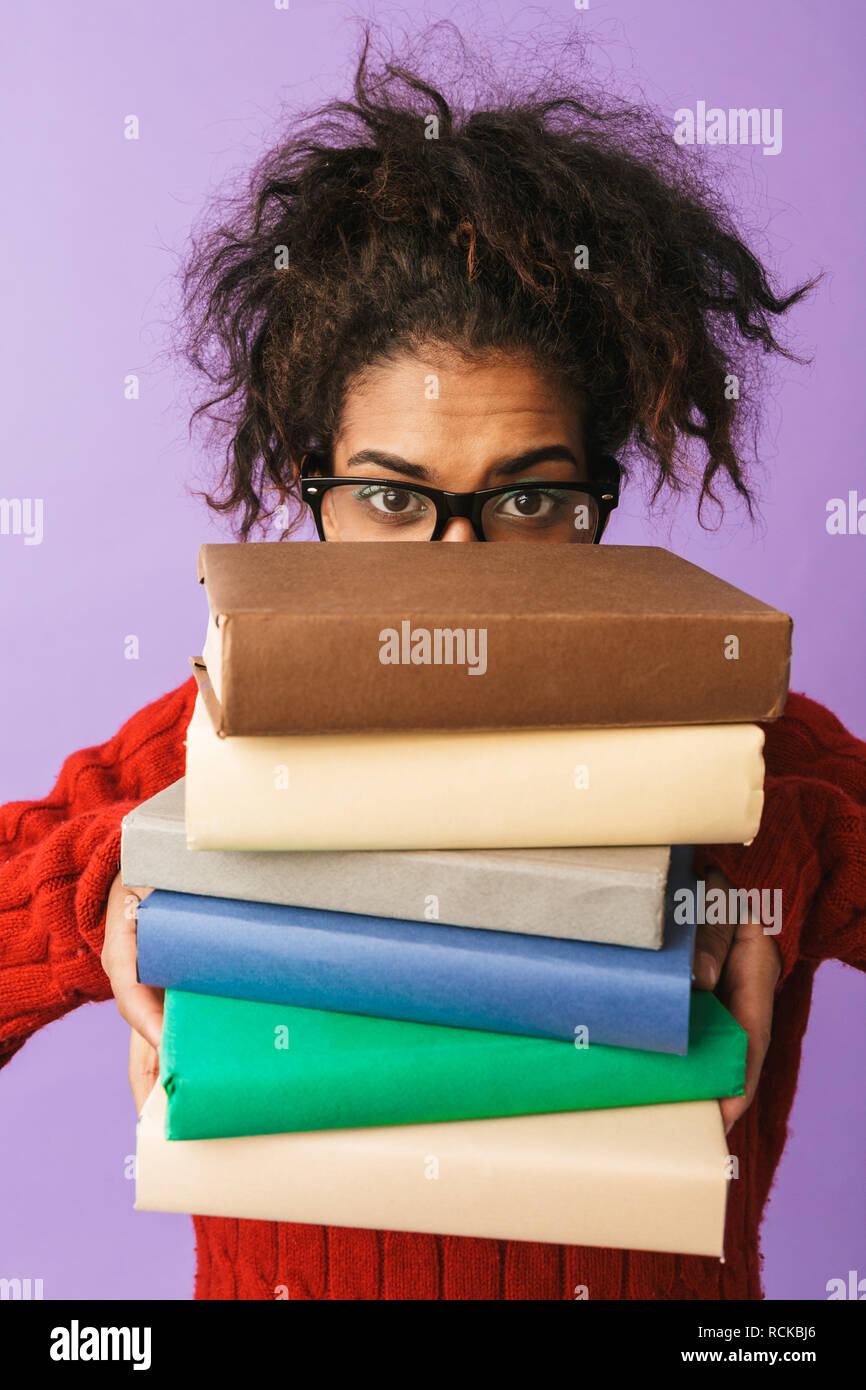African American funny girl in uniforme scolastica tenendo il mazzo di libri isolate su sfondo viola Foto Stock