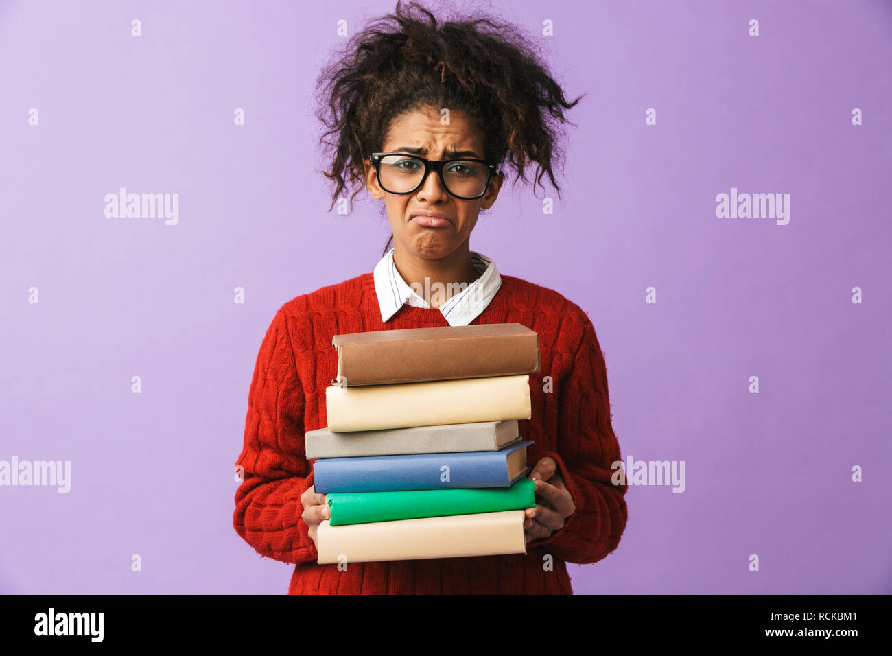 Americano africano ragazza ricalcato in uniforme scolastica tenendo il mazzo di libri isolate su sfondo viola Foto Stock