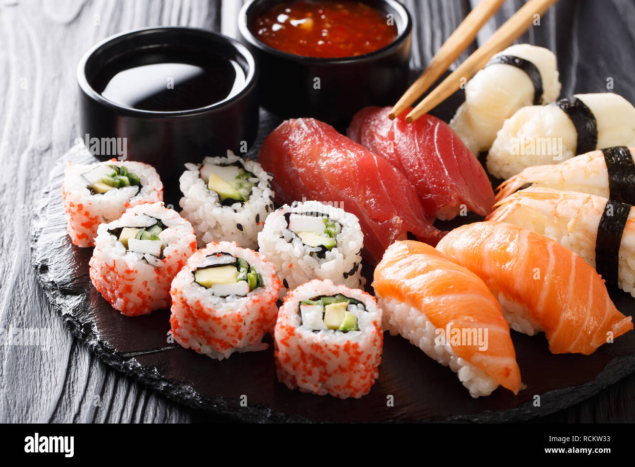 Set di fresco, maki uramaki e nigiri sushi, servita su piastra nera di close-up. Posizione orizzontale Foto Stock