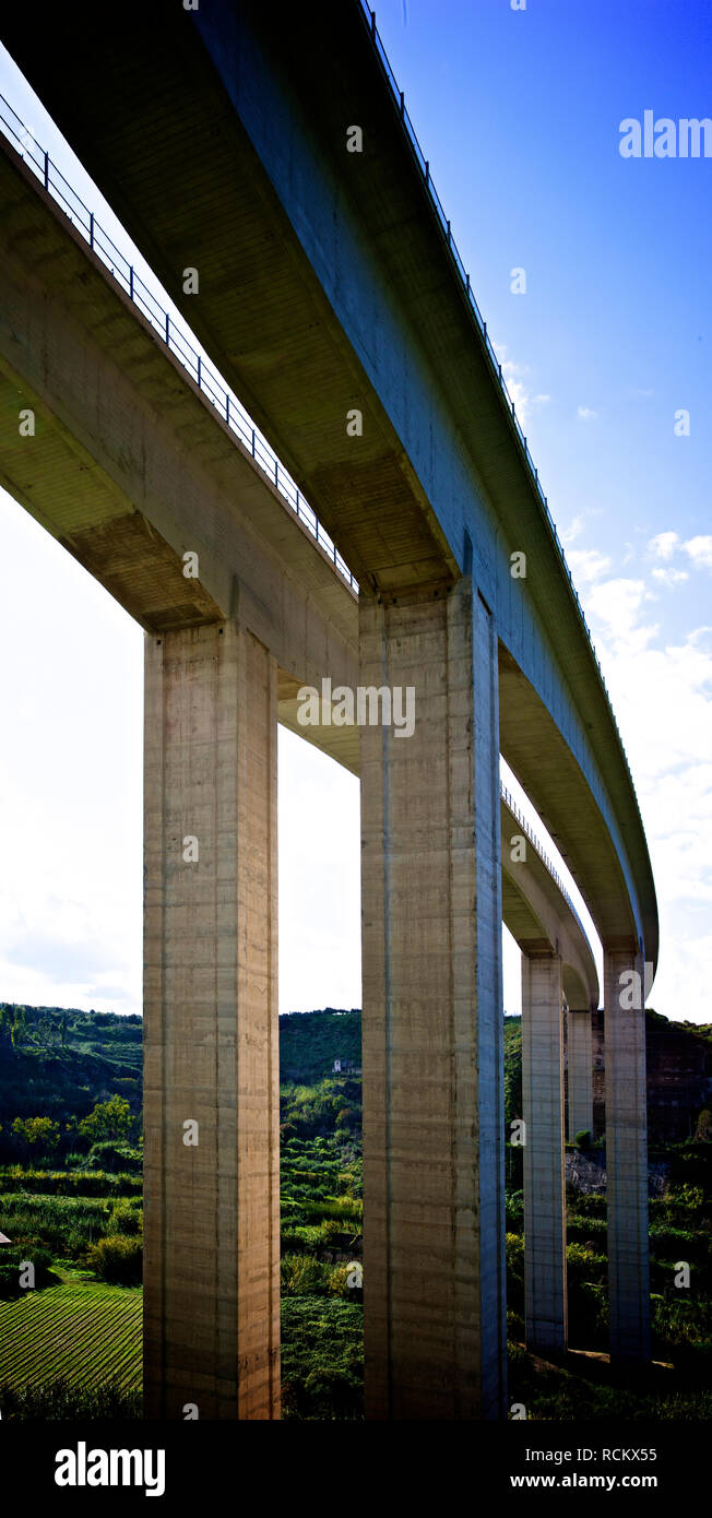 Vista dal basso in scala grande ponte stradale nelle ore diurne, che mostra la curva contro sky Foto Stock
