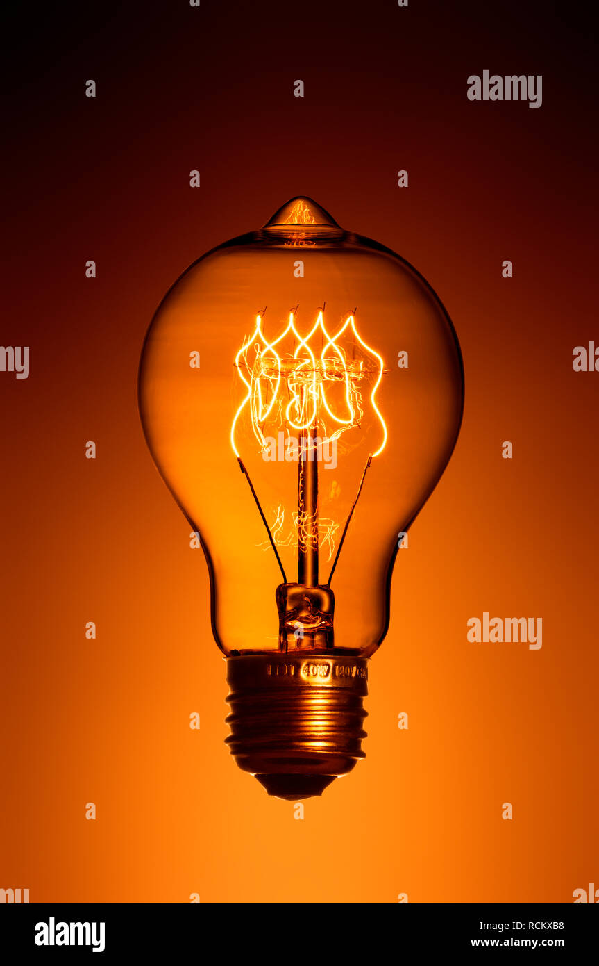 Retro illuminato lampadina con raccordo a vite, close up, orange Colore di sfondo Foto Stock