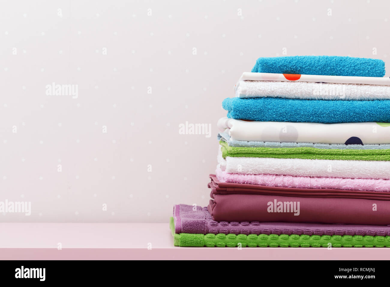 Sul comò vi è una pila di pulire stirare la biancheria da letto e ripiegato asciugamani colorati. Foto Stock