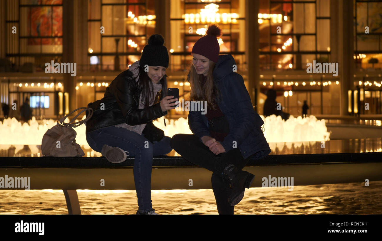 Due ragazze hanno una fantastica notte di New York mentre è seduto a una fontana Foto Stock