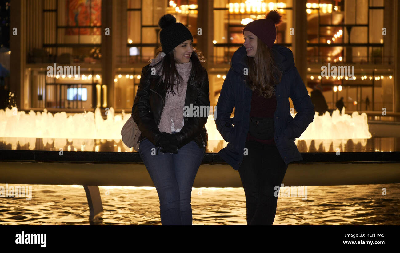 Due ragazze hanno una fantastica notte di New York mentre è seduto a una fontana Foto Stock
