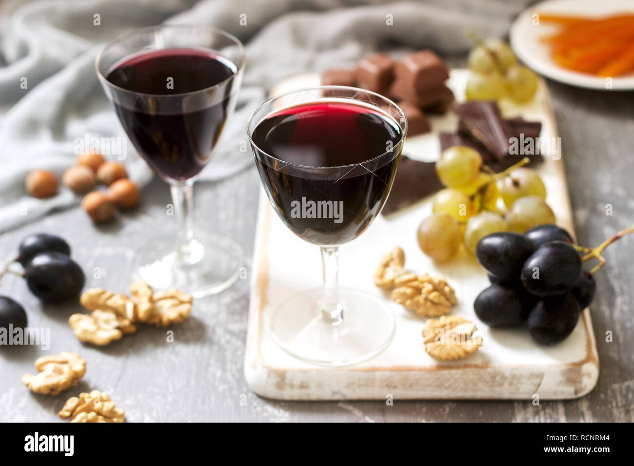 Crème de Cassis liquore casalingo servita con uve, noci e cioccolato. In stile rustico, il fuoco selettivo. Foto Stock